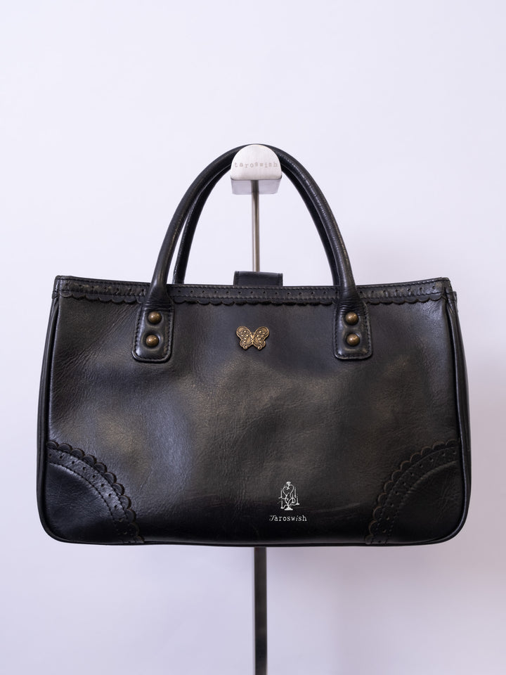 Anna Sui black leather mini tote bag with butterfly emblem and scalloped corner stitching.