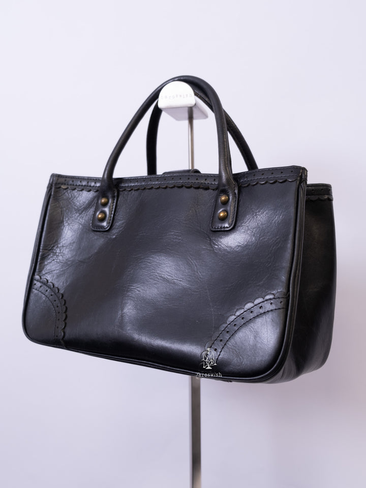 Anna Sui black leather mini tote bag with butterfly emblem and scalloped corner stitching.