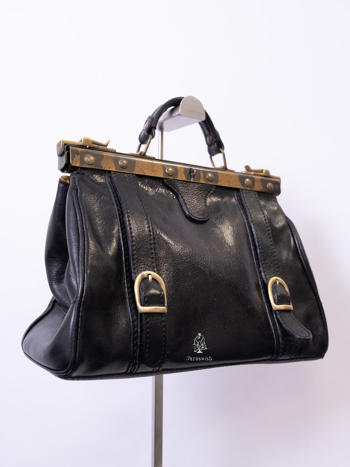 Black leather doctor-style bag with brass frame and buckle accents.