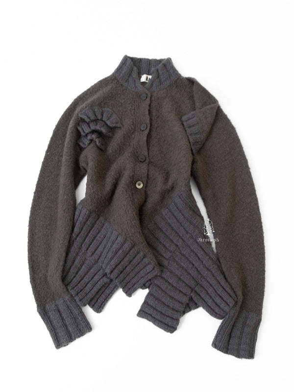 Grey sculptural knit cardigan with ribbed panels and asymmetrical textured details.